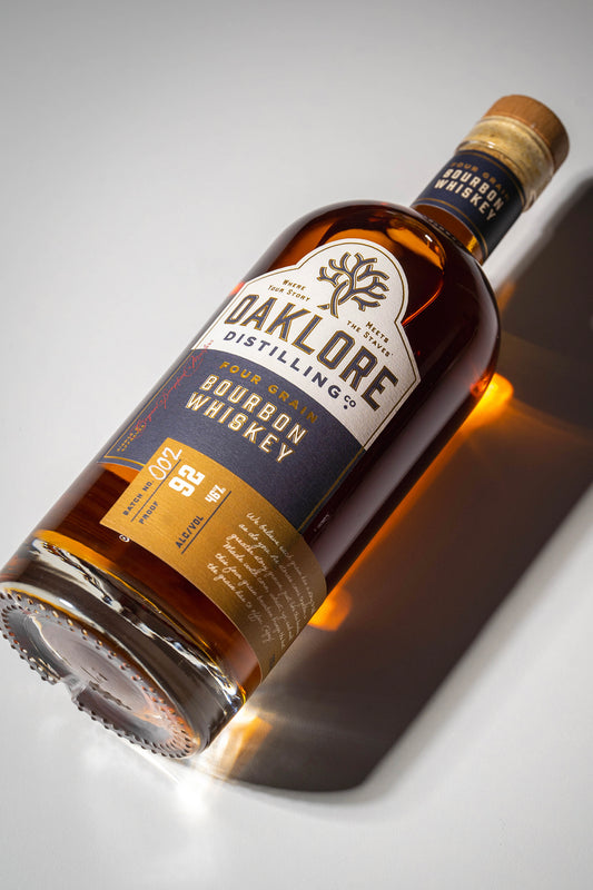 Oaklore Distilling Co. Four Grain Bourbon Whiskey bottle laying down on a white backdrop